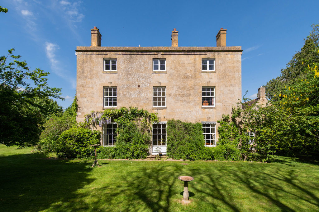 The Old Vicarage, Mickleton georgian double fronted cotswold stone property with white pane windows and wisteria sitting in front of gardens