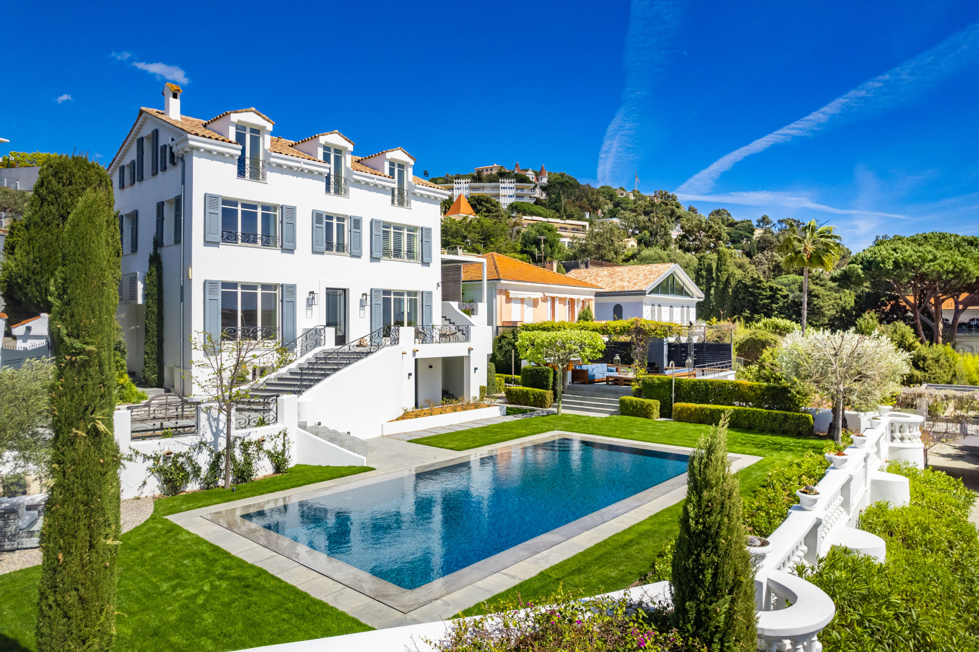 view of white french villa with gardens and pool