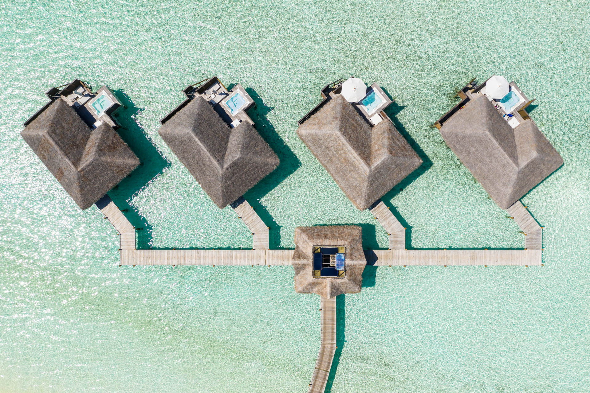 closer aerial view of huts in turquoise sea