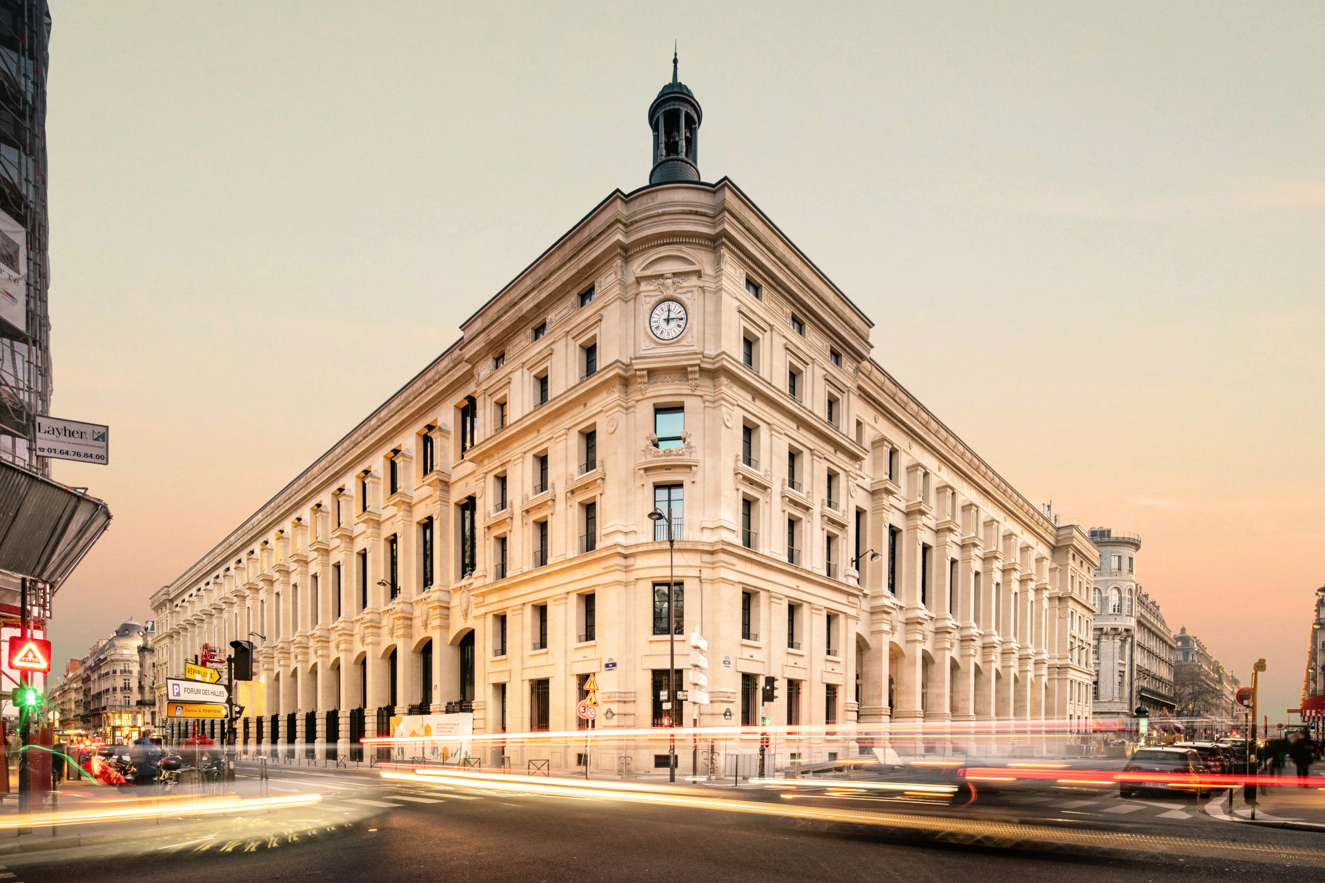 facade of hotel madame reve - traditional parisian building in between two streets with sunset