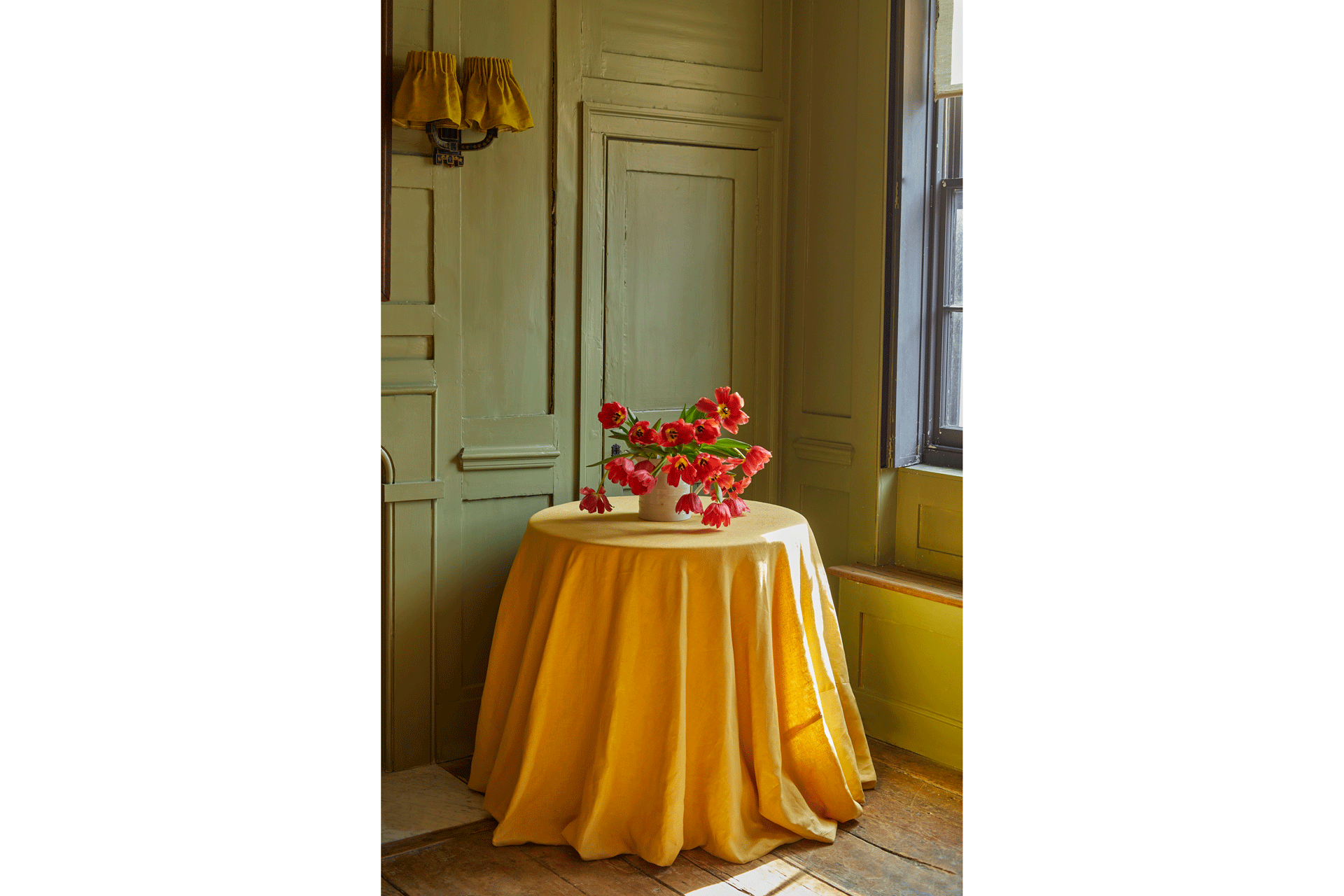 A yellow tablecloth with red tulips, called The Chartreuse Cloth by East London Cloth