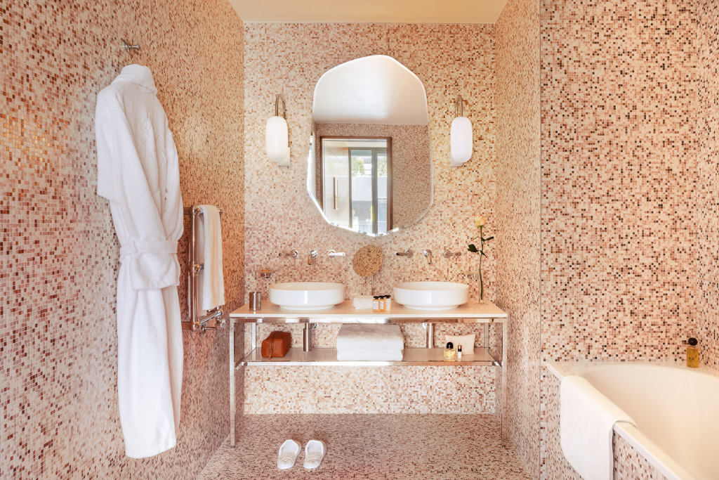 pretty pink marble style bathroom with double sink, mirror and white dressing gown hanging up 