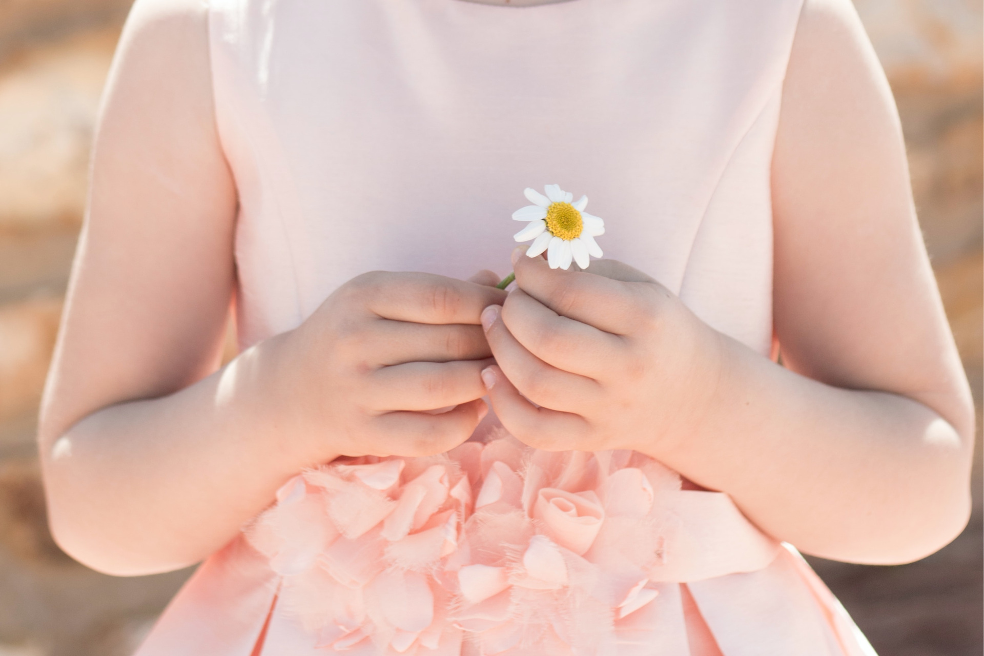 Close up of a flower girl holding a daisy