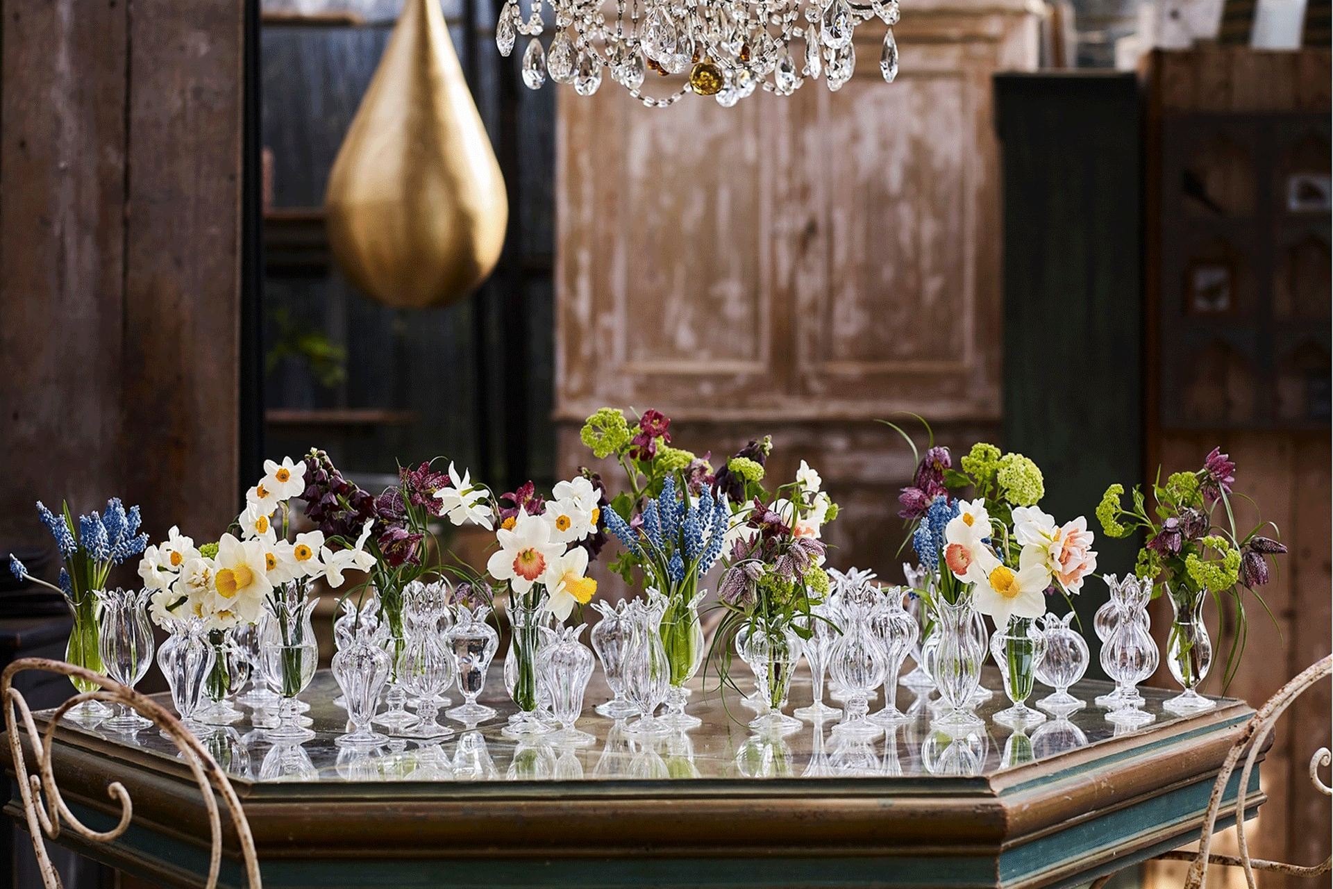 a group of bud vases on a mirrored table at Petersham Nurseries