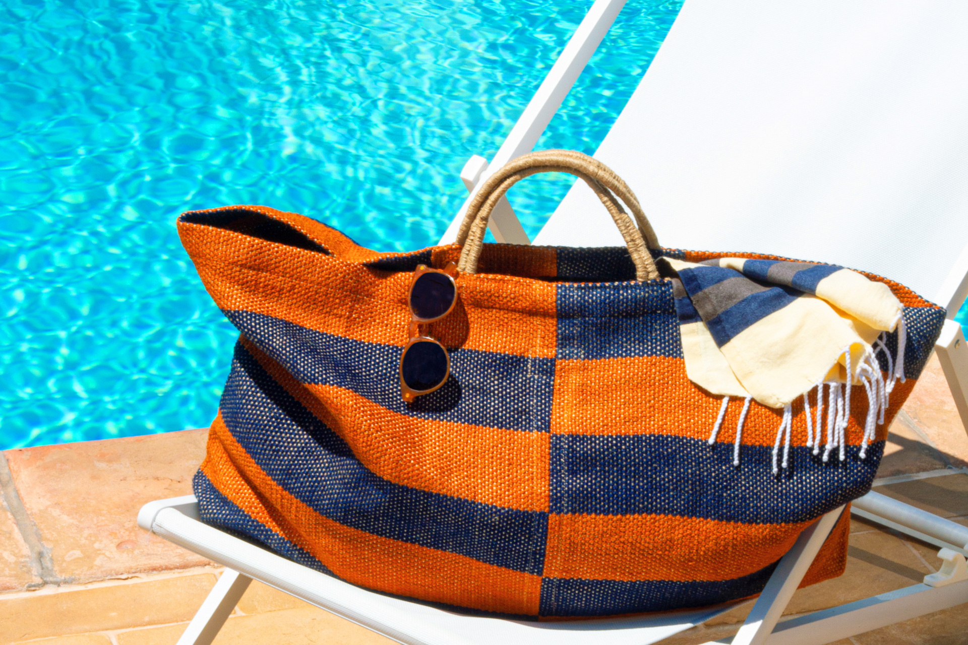 Navy and orange check striped bag on a sung lounger by the pool