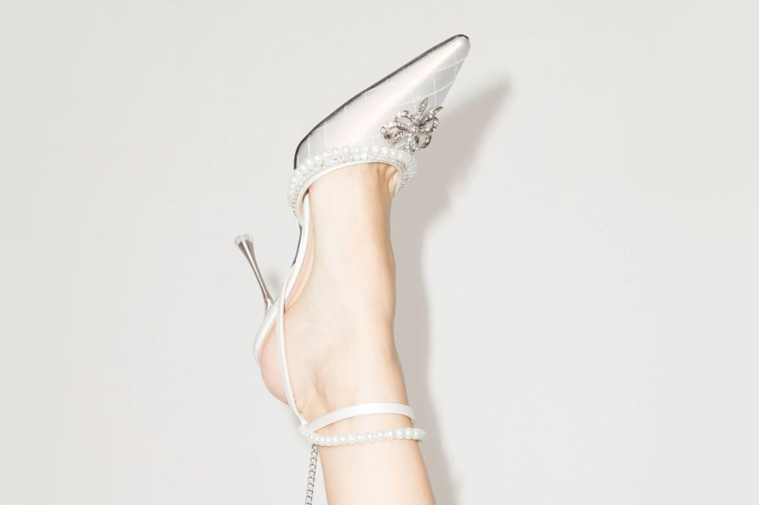 One foot in the air wearing a silver and ivory shoe