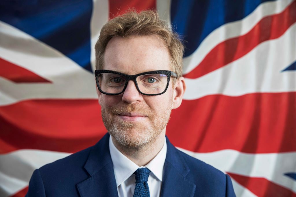 Tom Davies wearing glasses with union jack background