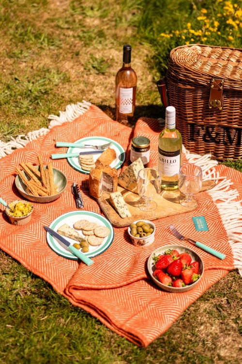 Orange Fortnum & Mason picnic blanket with basket and food setup