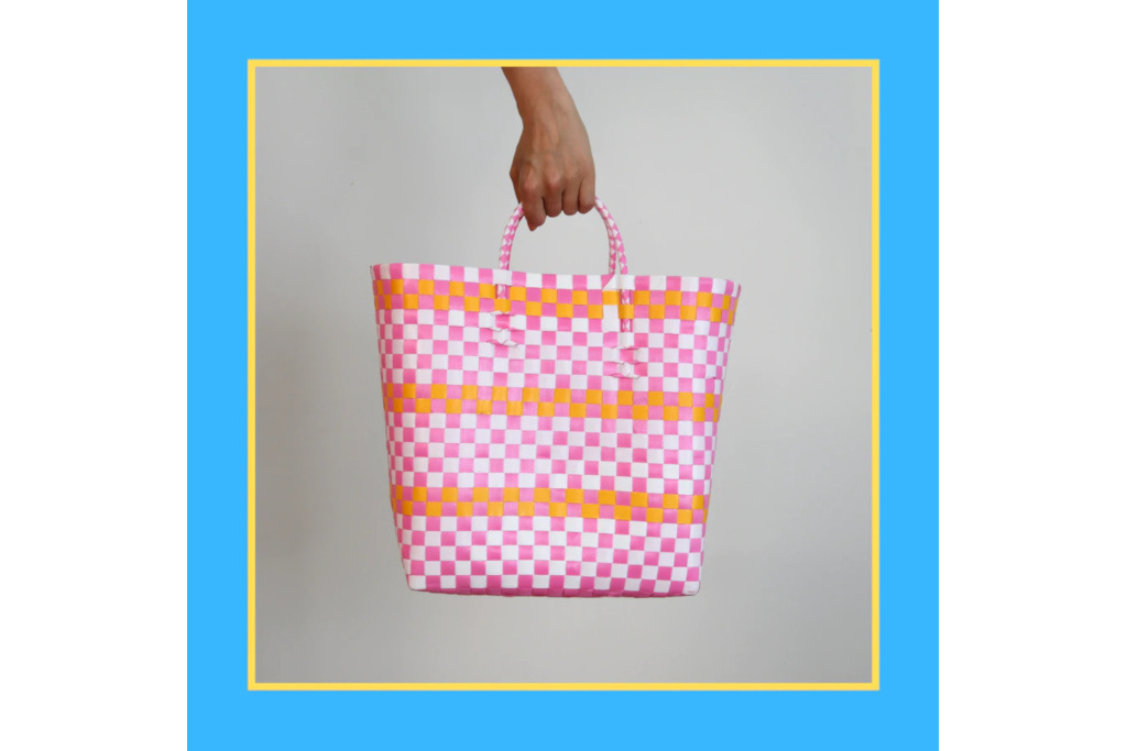Hand holding a pink, orange and white checked bag, with a blue and yellow border