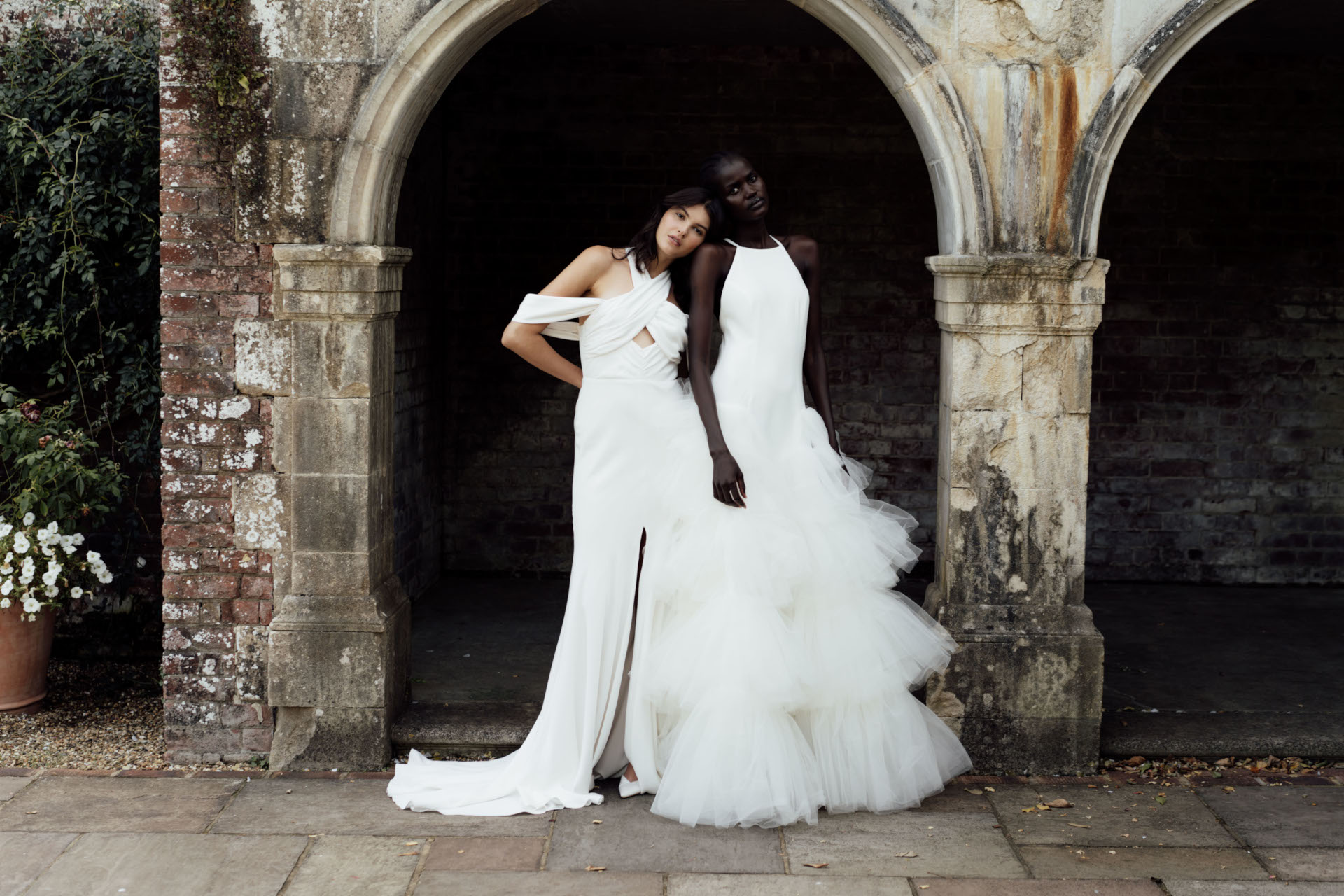 Two models in white dress stood in stone arch