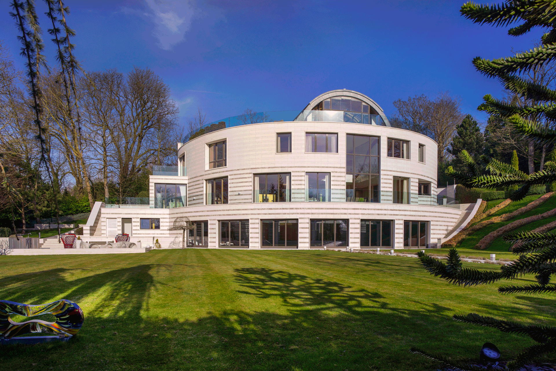 Large carved mansion with glazed sections and a water feature.