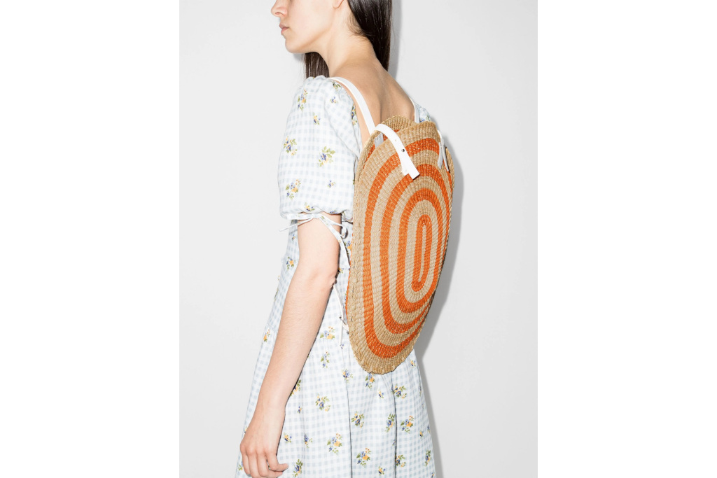 Model with back to the camera, wearing an oval striped woven rucksack