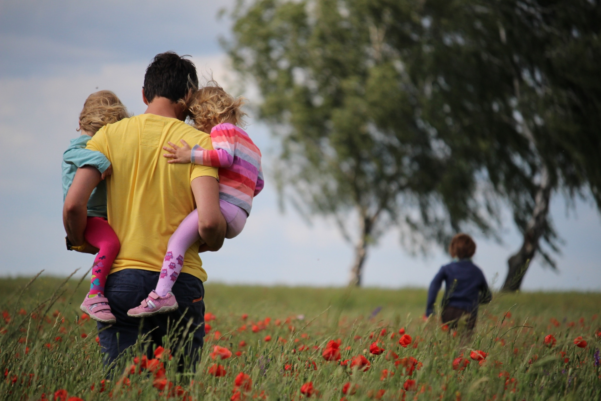 Dad carrying kids through flower field