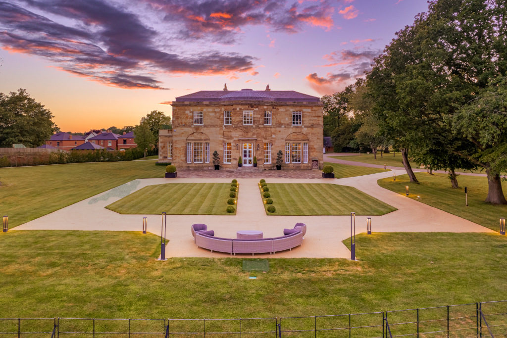 exterior of a country grade II listed mansion in rugby, in the evening with smart grounds in front