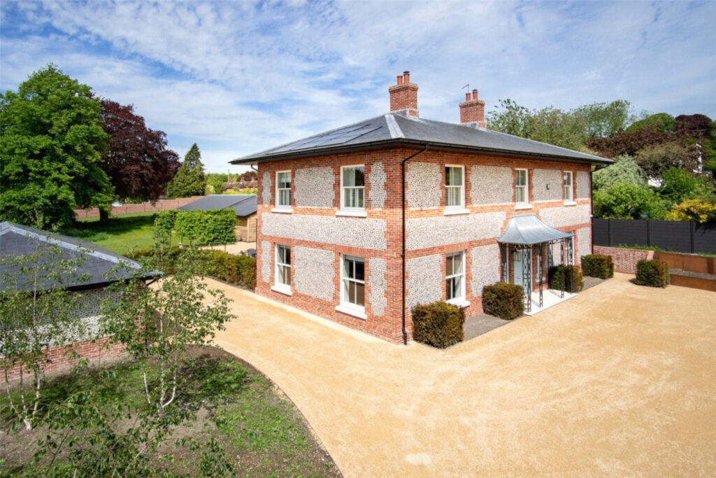 Aerial view of a country home, red and brown brick with sandy gravel drive