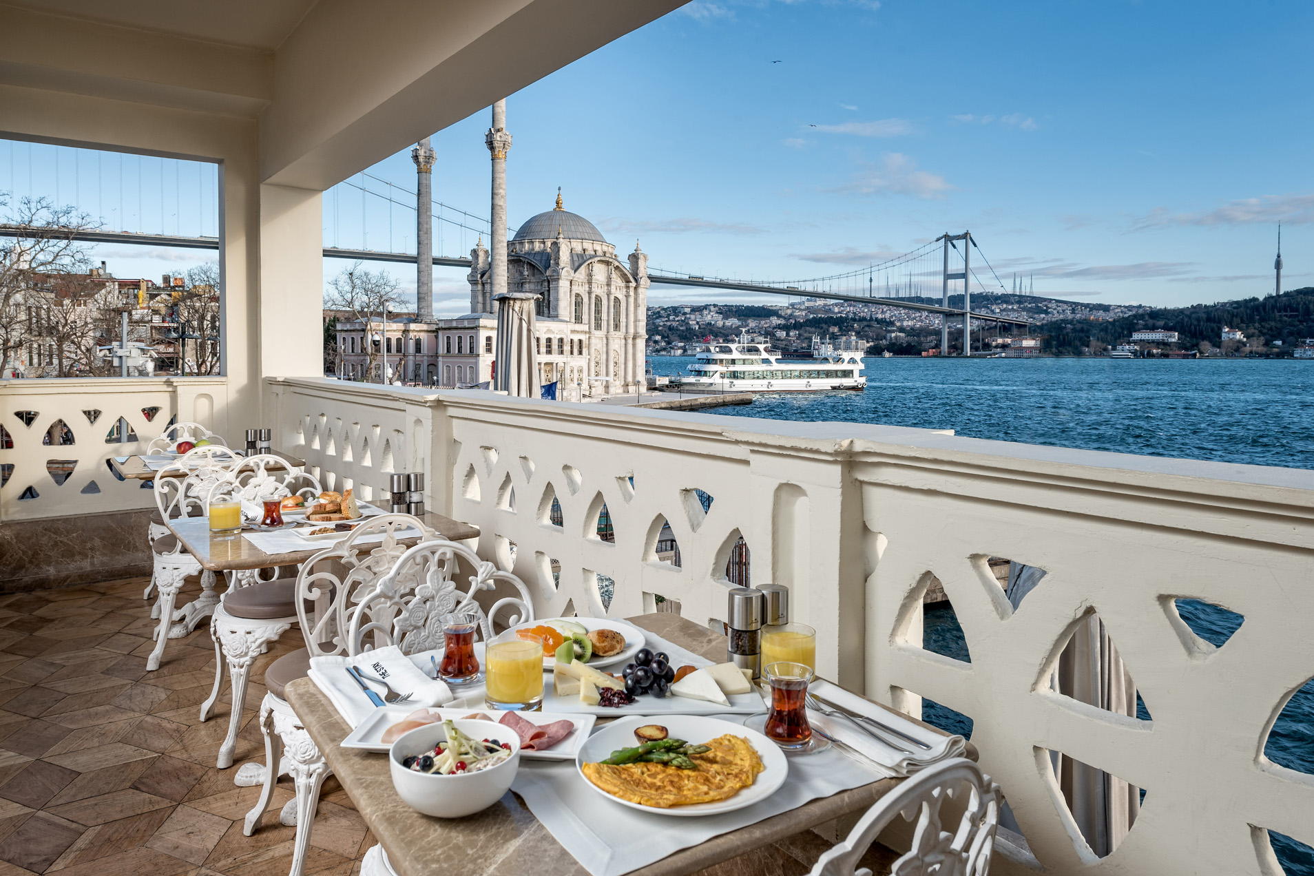 Tables laid with plates, cutlery and breakfast food, overlooking the water in Istanbul