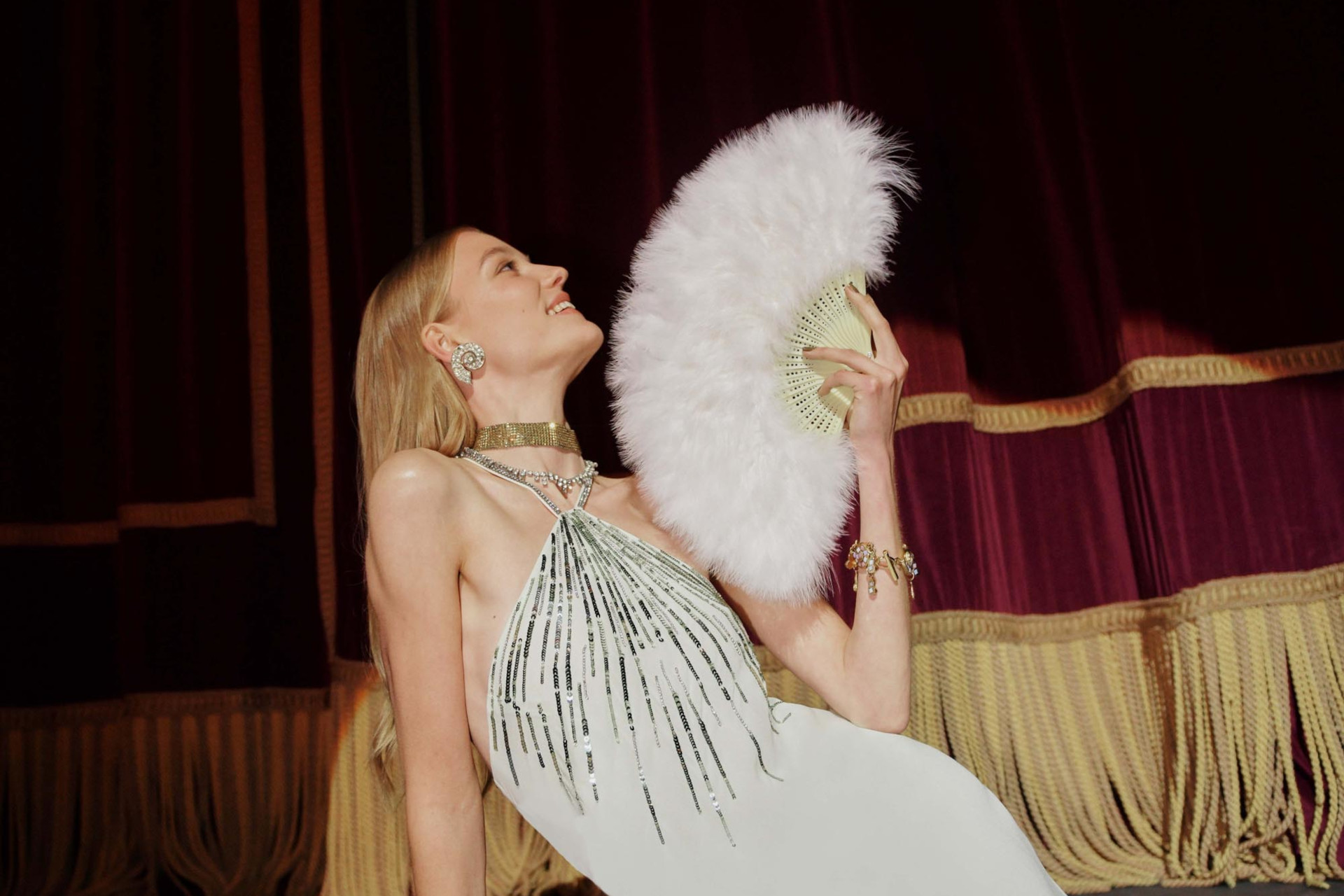 Woman leaning back in white dress with feather fan