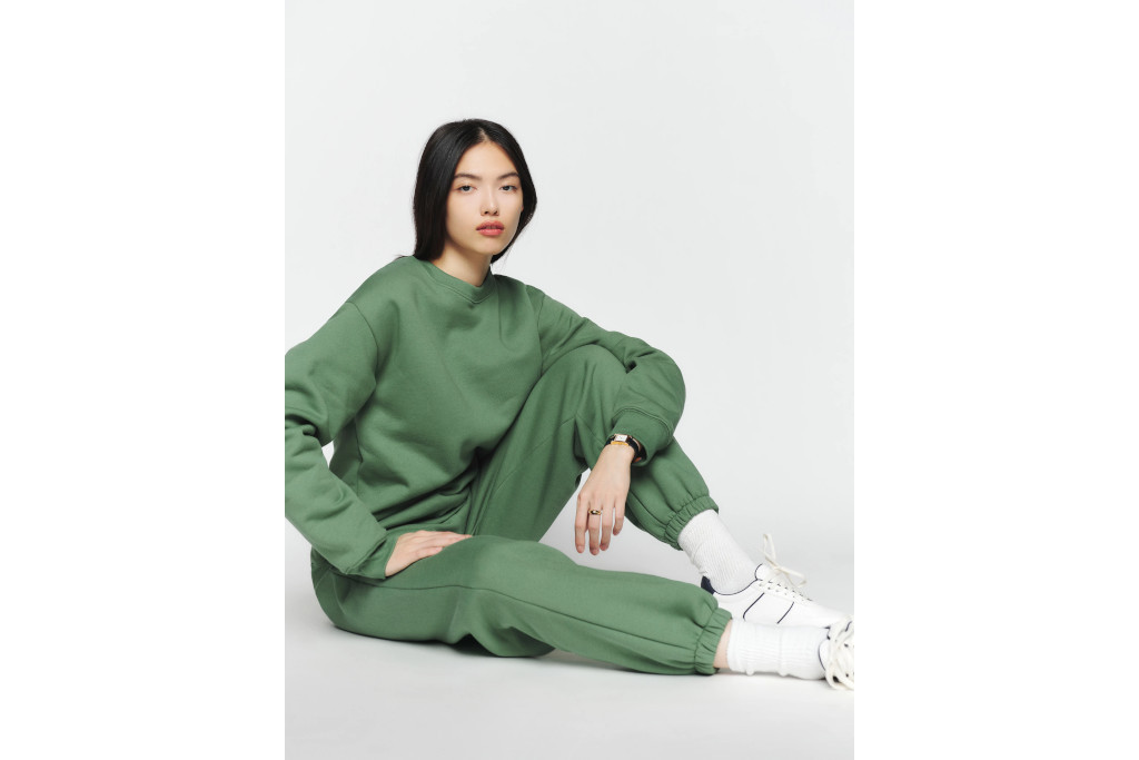 Model sat down in green jumper and joggers