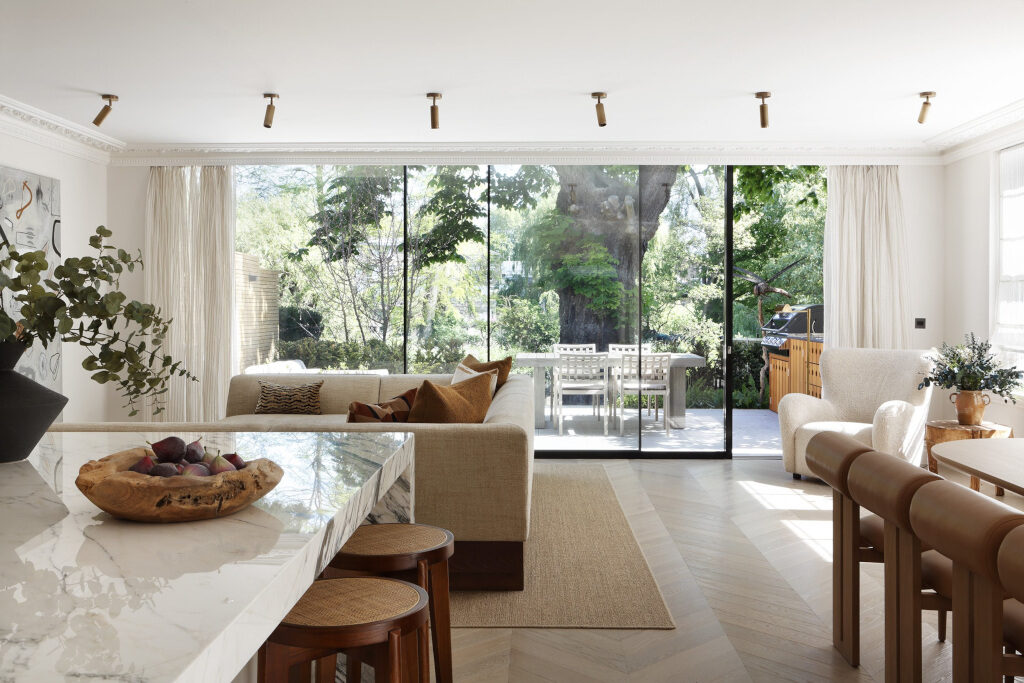 Open plan kitchen and living room with floor to ceiling windows leading to outdoor sitting and dining space