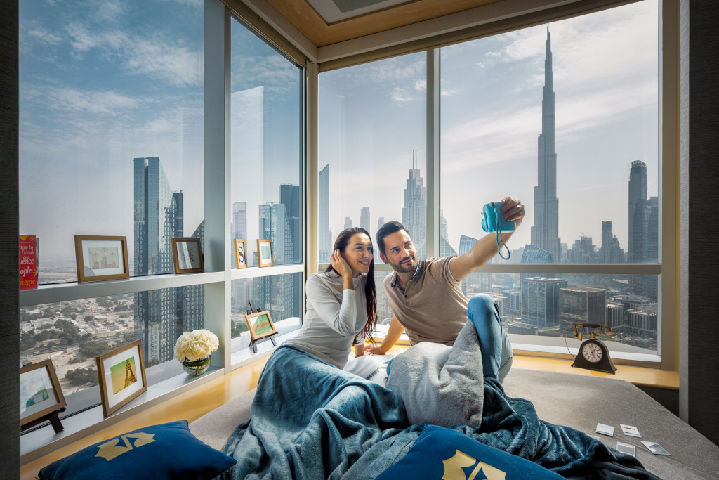 couple taking selfie on polaroid at Shangri-La Dubai with background of cityscape behind