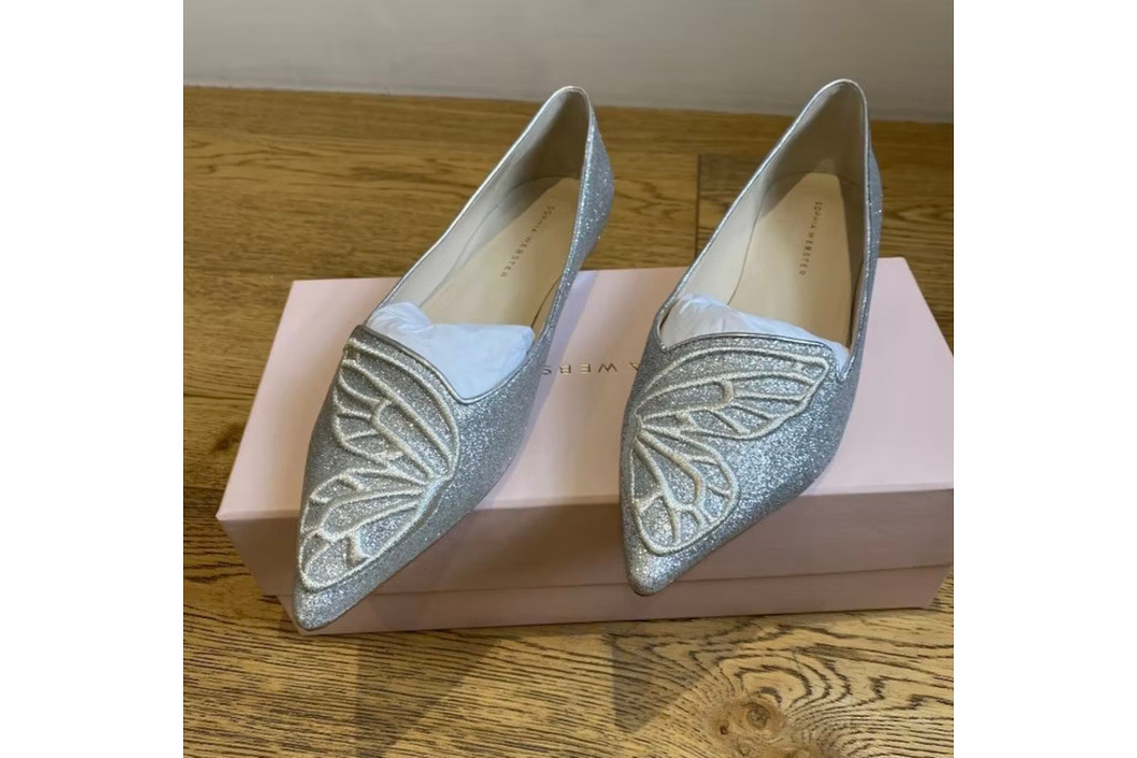 Silver pumps with butterfly wing decoration on the toes sat on pink shoe box on wooden table