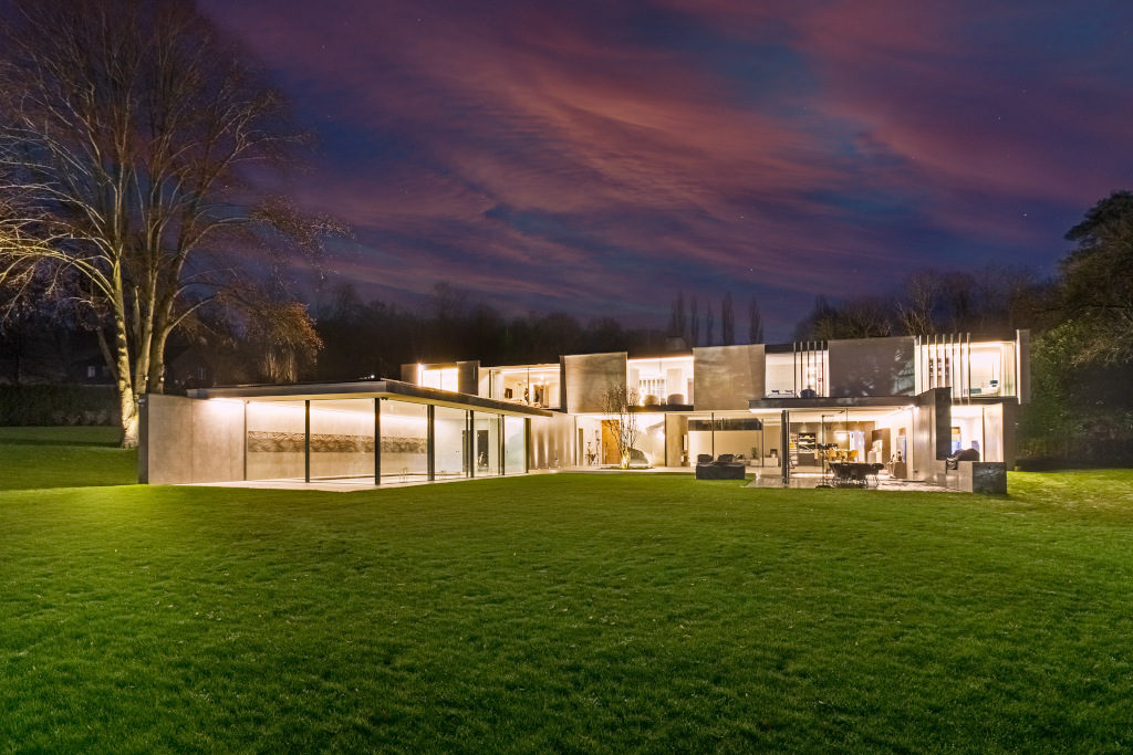 exterior shot at night of ultra modern home with glass windows and walls in Hertfordshire