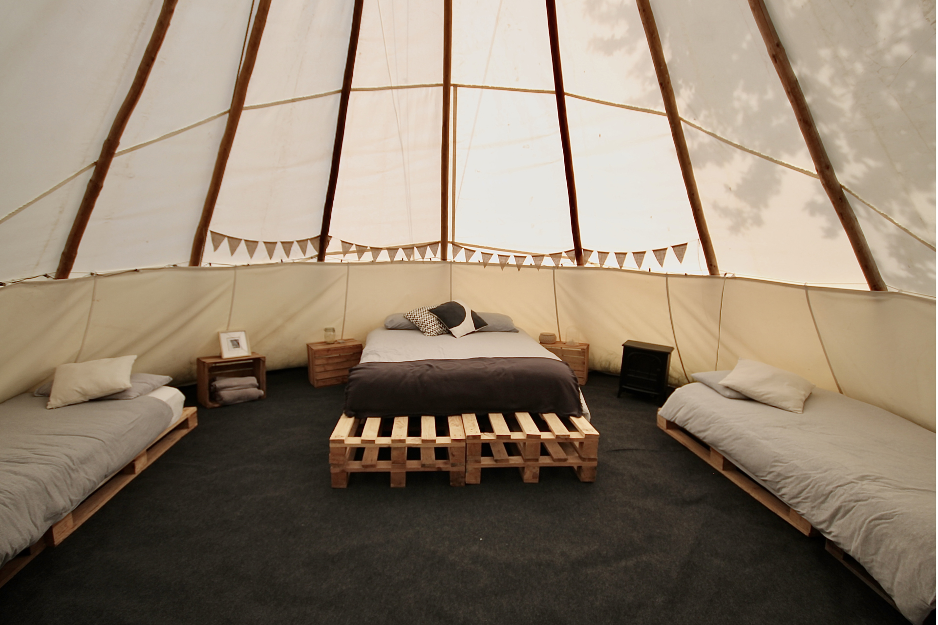 A spacious tipi with double bed in the middle, flanked by two single beds
