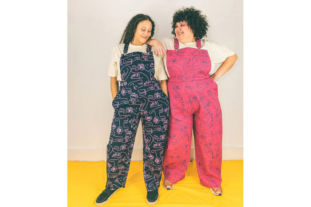 Two models stood in colourful dungarees, on yellow floor and cream background