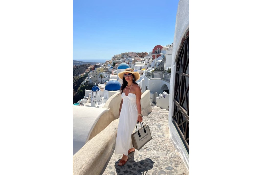 Woman in a yellow dress and sun hat, holding a bag and walking down sunny streets