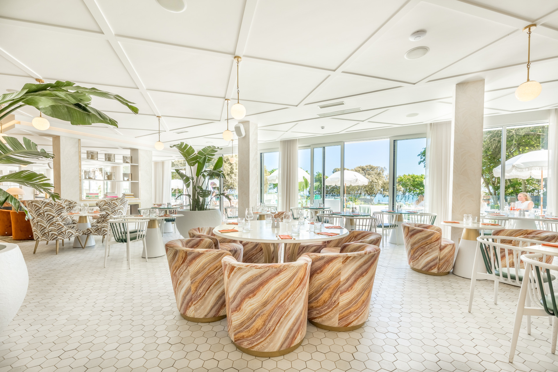 The Nici restaurant & Terrace with light, white interiors in a large room and chairs with swirls round table