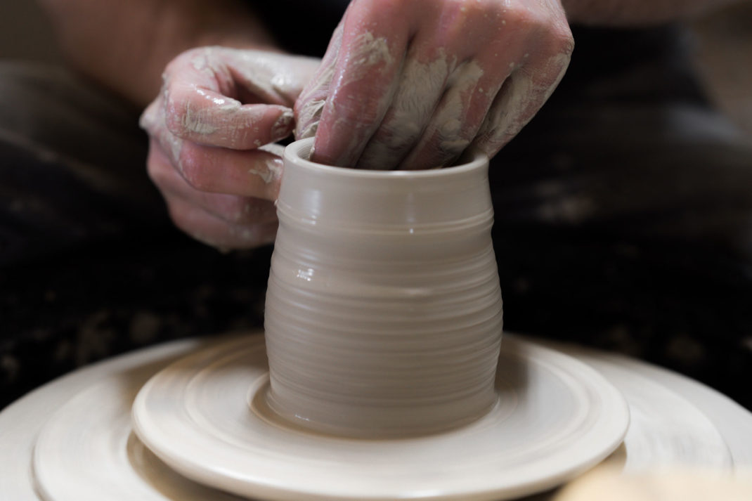 hands making a pot on a pottery wheel 