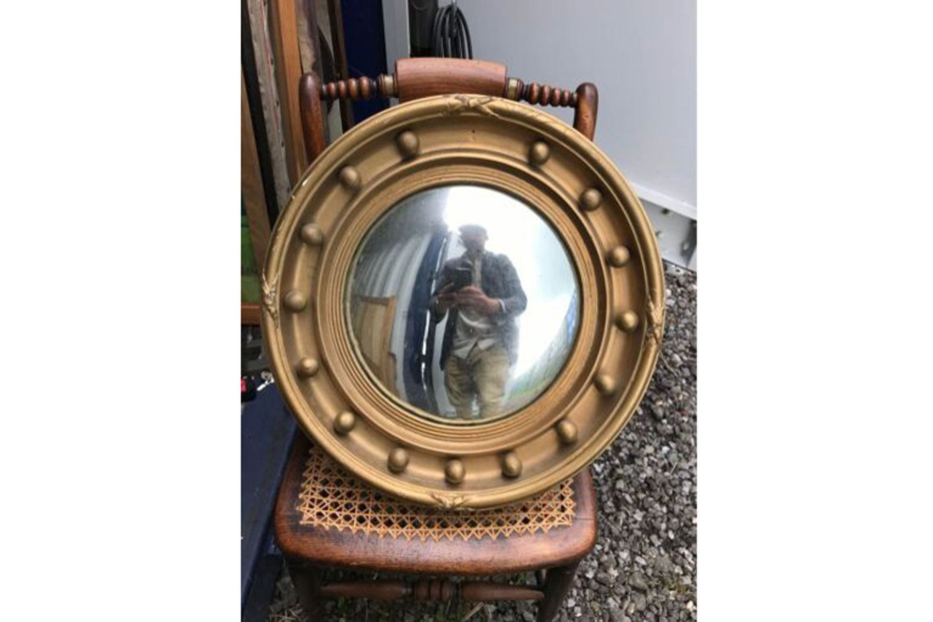 a convex antique porthole mirror standing on a chair, sold by eBay