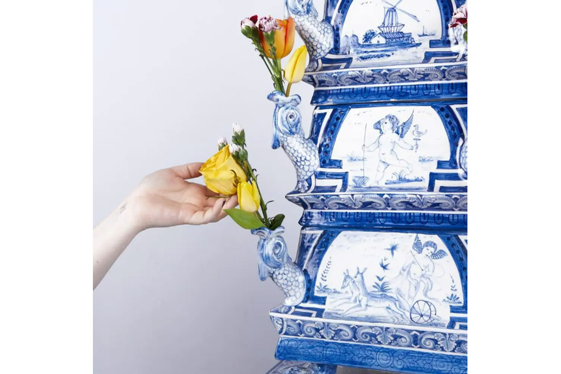 a hand puts a yellow rose in an antique tulipiere, sold by 1st Dibs