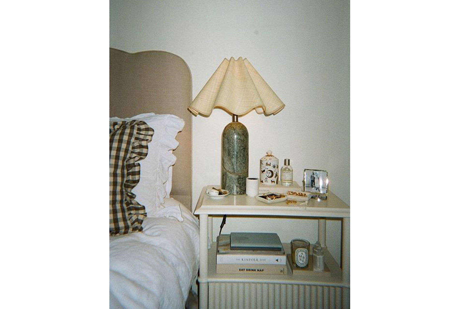 an image of a scallop finished lamp bedside table, with a ruffle pillow and kinfolk magazine