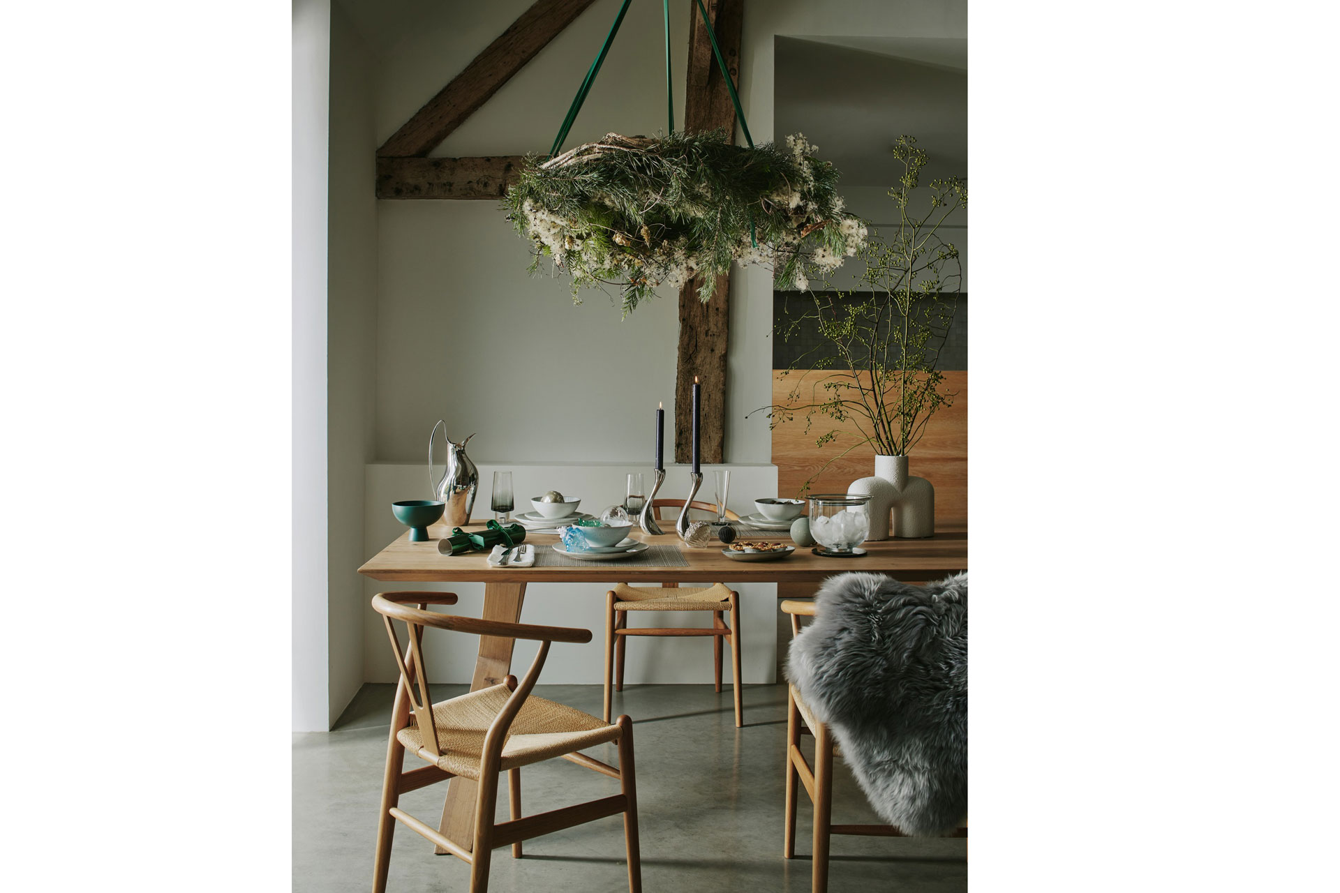 the interior of a kitchen with wooden chairs and table with a wreath suspended overhead