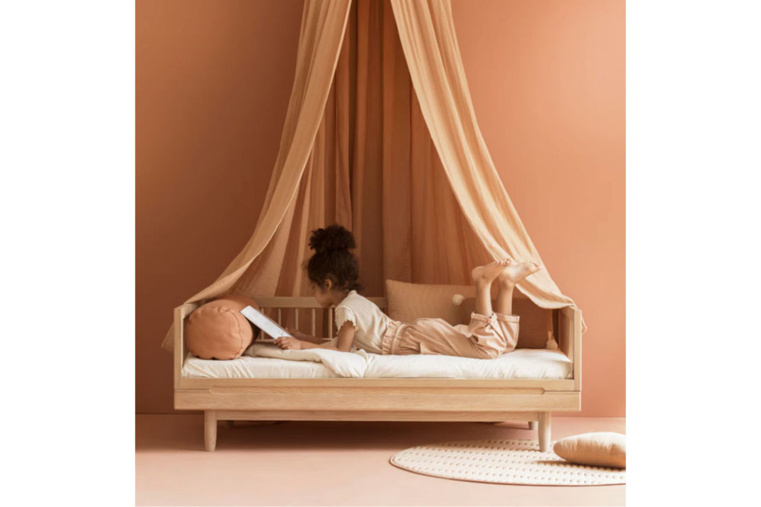 a pink bed for kids with a curtain canopy overhead
