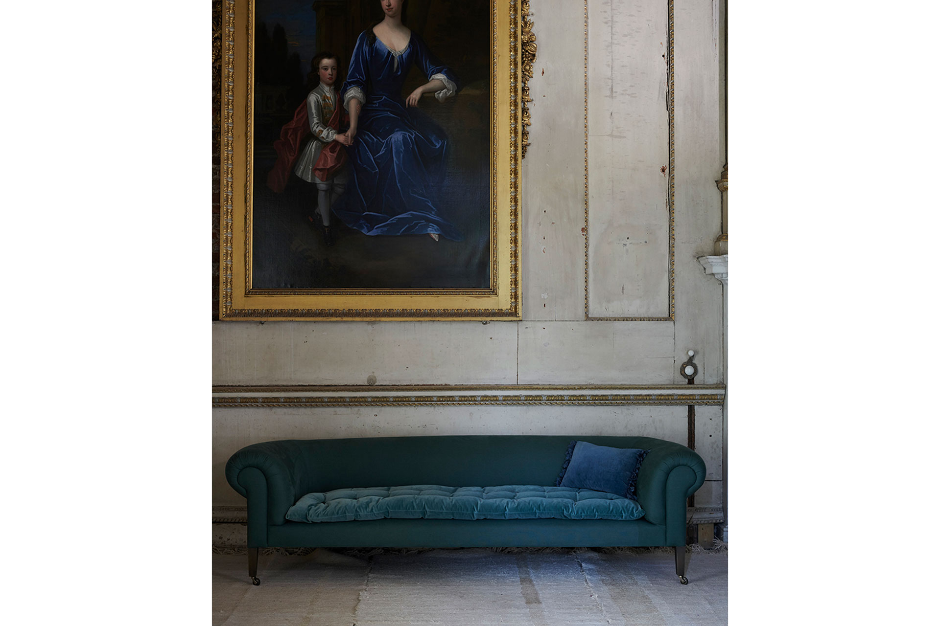 a blue sofa in front of an historic wall with a beautiful grand painting above