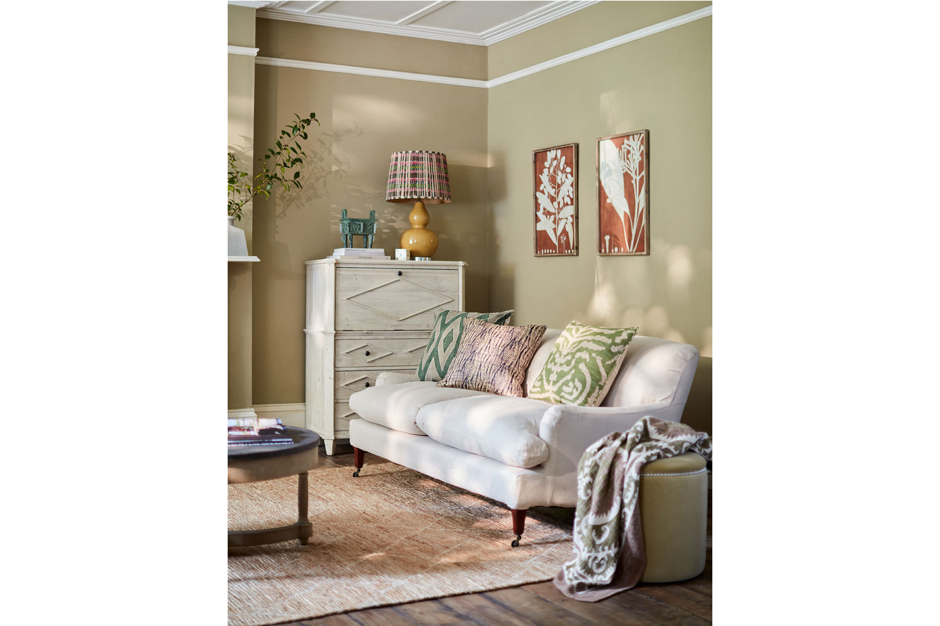 a living room with green walls and a cream sofa, that's all from Oka, a furniture brand