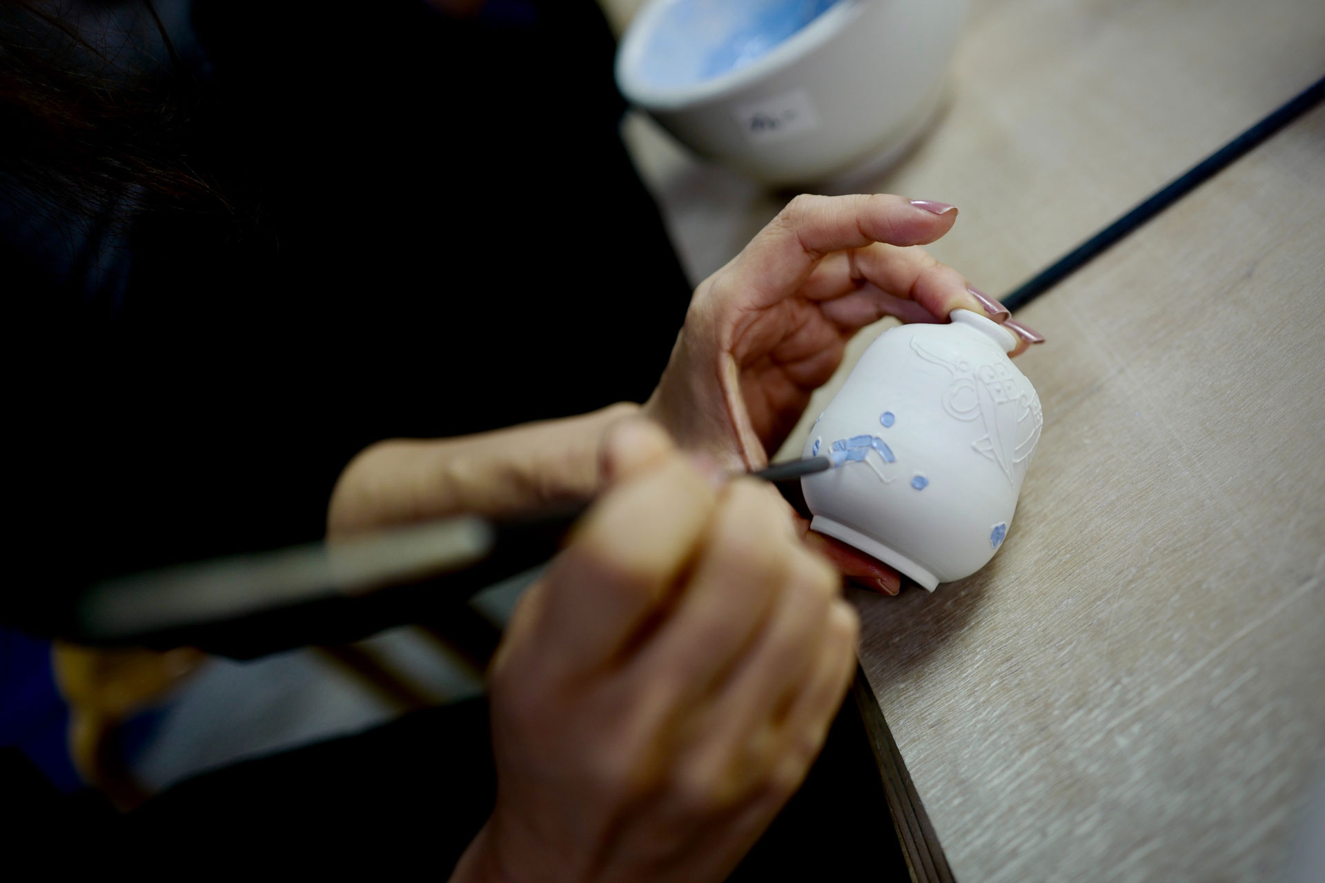 a close up of someone painting a pot with paint at a pottery