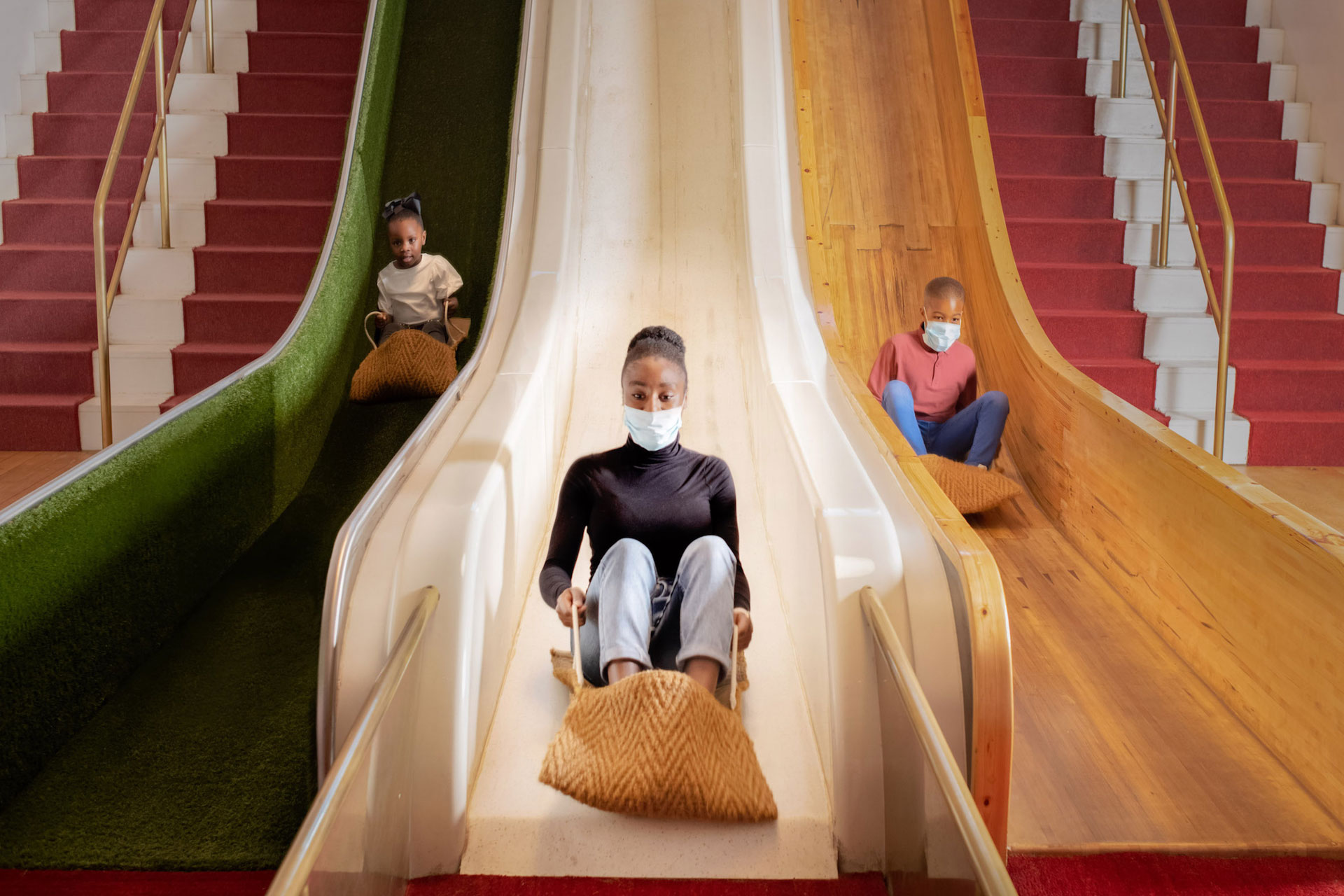 three kids sliding down a green white and yellow slide at The Science Museum in London