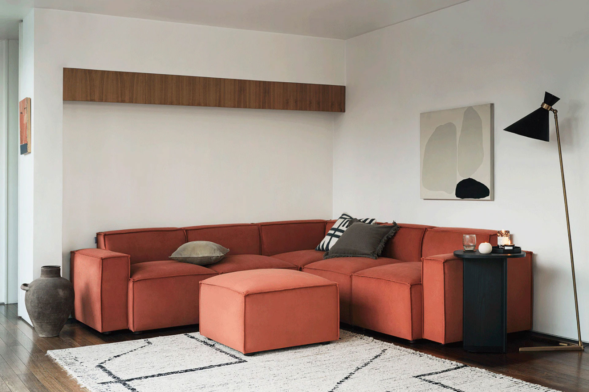a red Swyft corner sofa in a living room with a rug and standing lamp