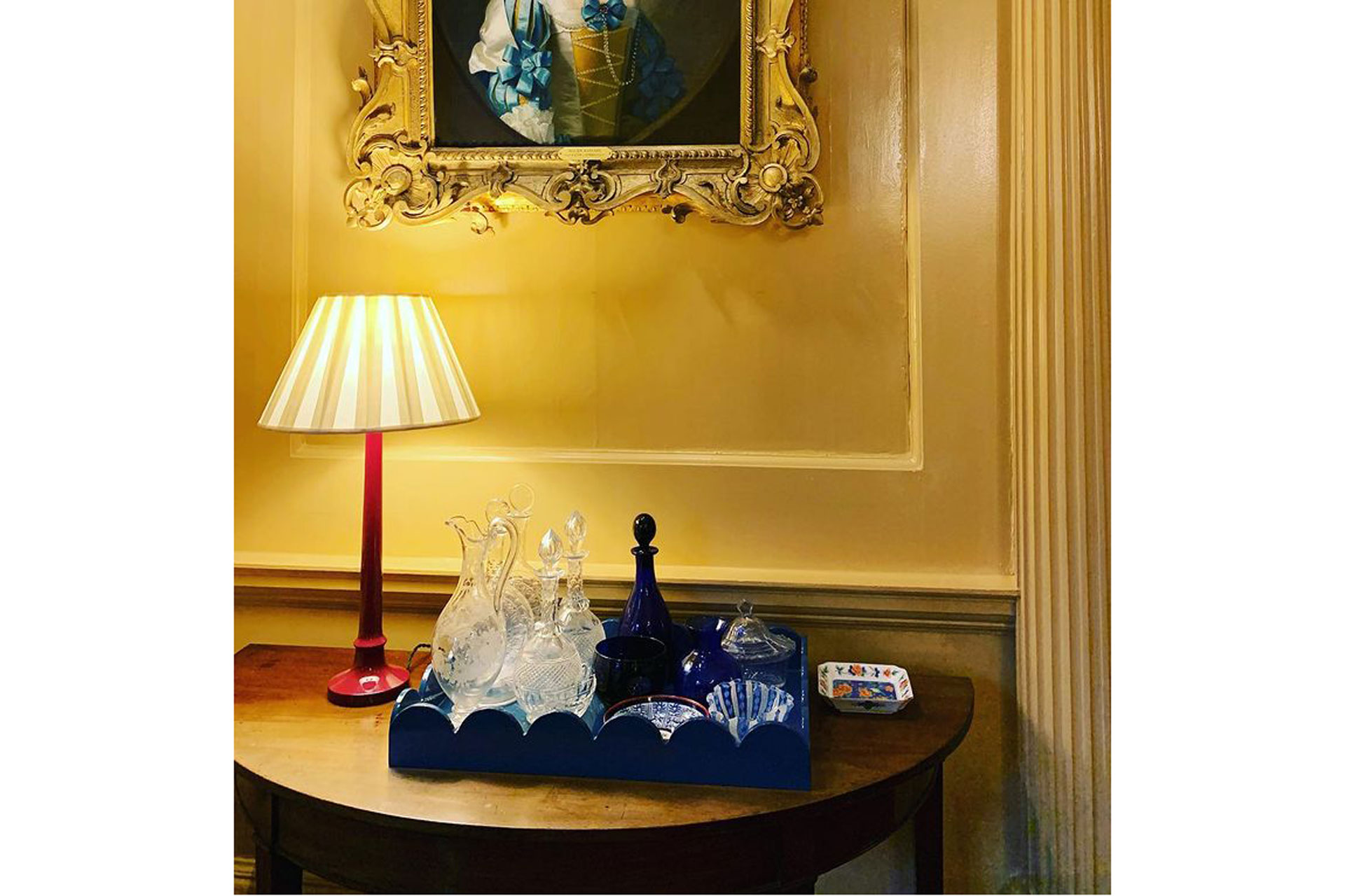a blue scalloped tray in a historic interior with yellow walls and historic painting