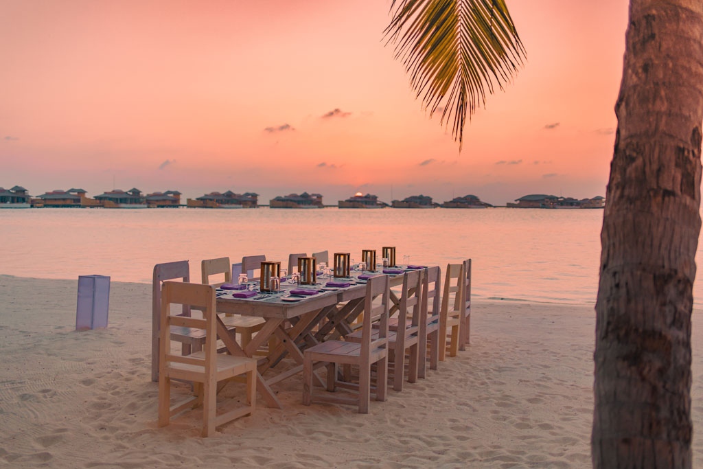 Soneva Jani So Primative alfresco dining table outside in evening on beach