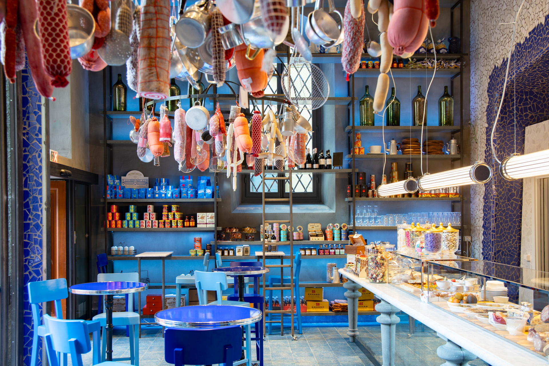 a blue restaurant with cured meat hanging from the ceiling 