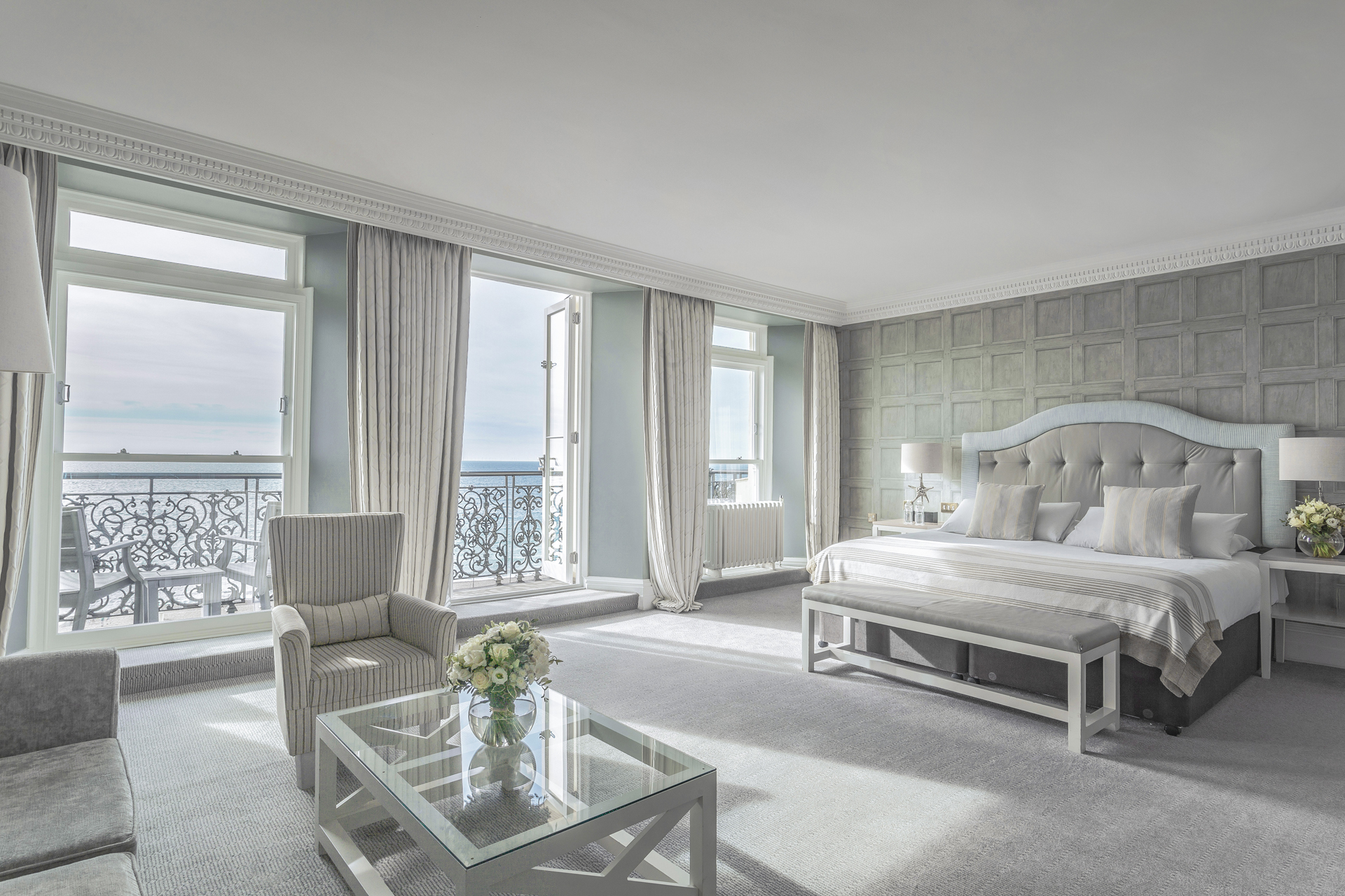 A light and airy bedroom with open balcony doors overlooking the sea