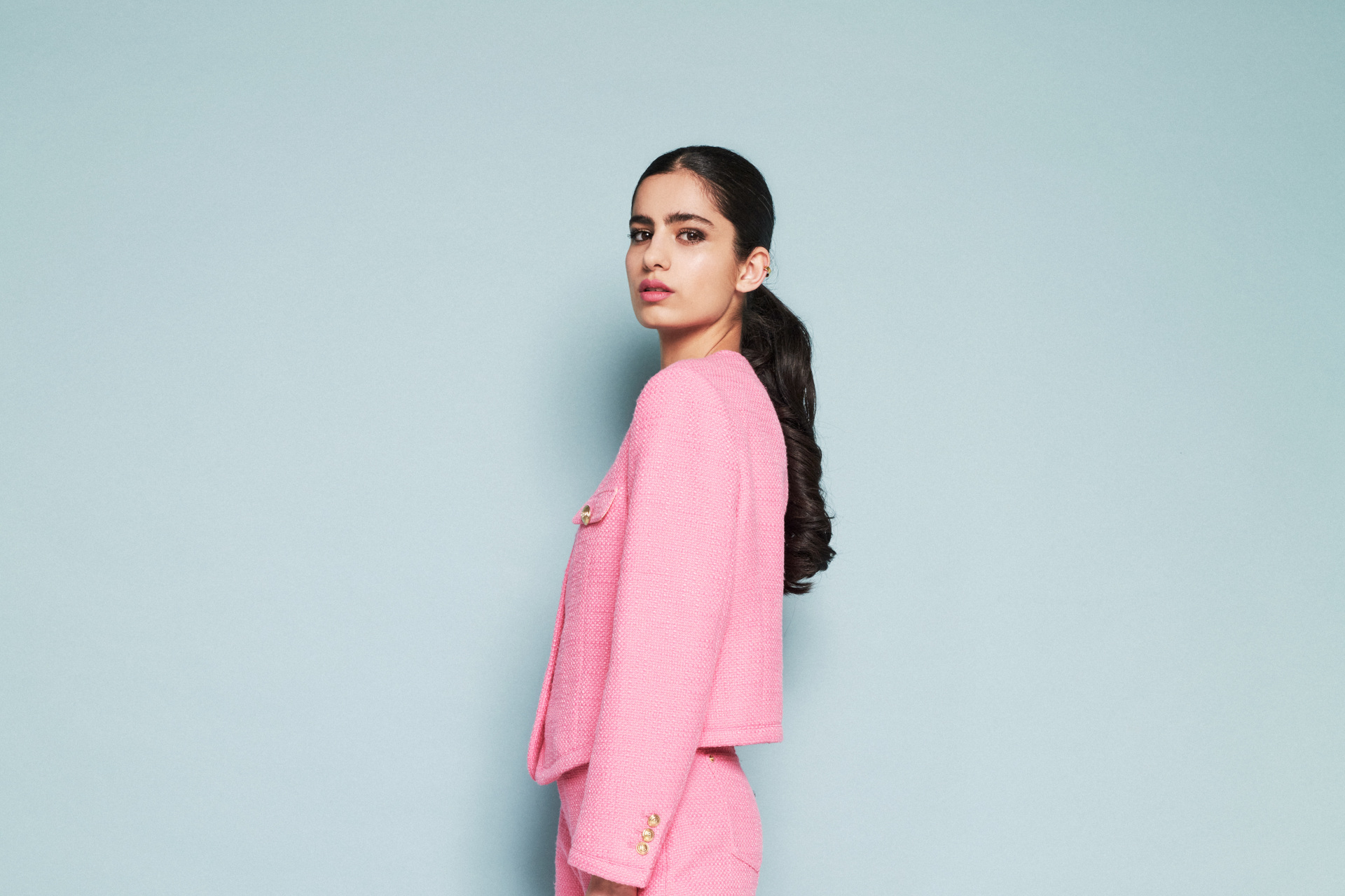 Hannah Khalique-Brown in pink suit, stood in front of mint coloured background