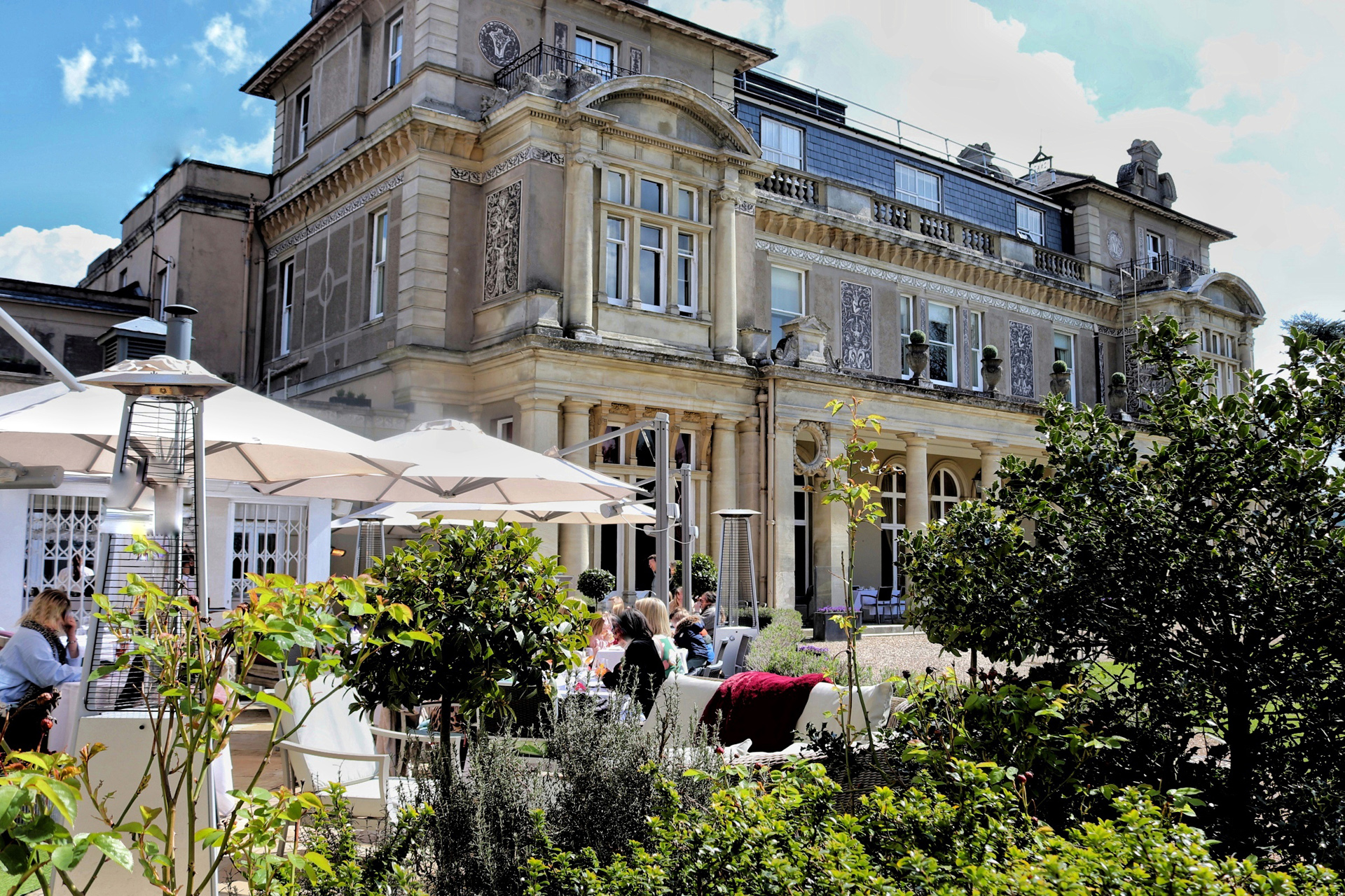The rear terrace at Down Hall, with parasols and guests sat in the sun