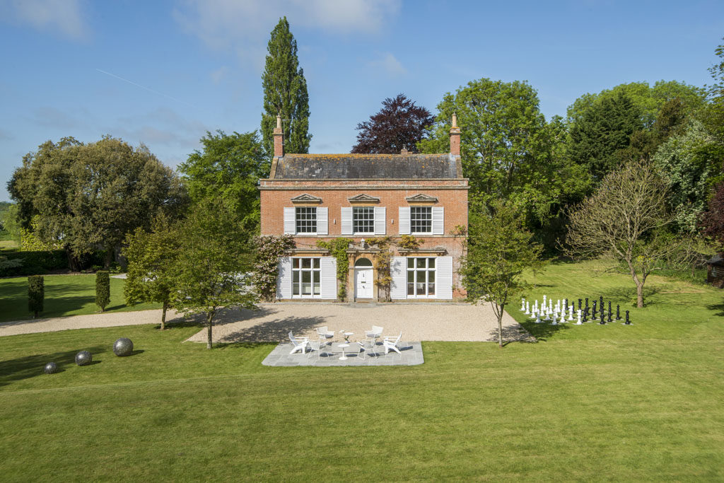 double fronted red brick georgian home with white shutters and wisteria
