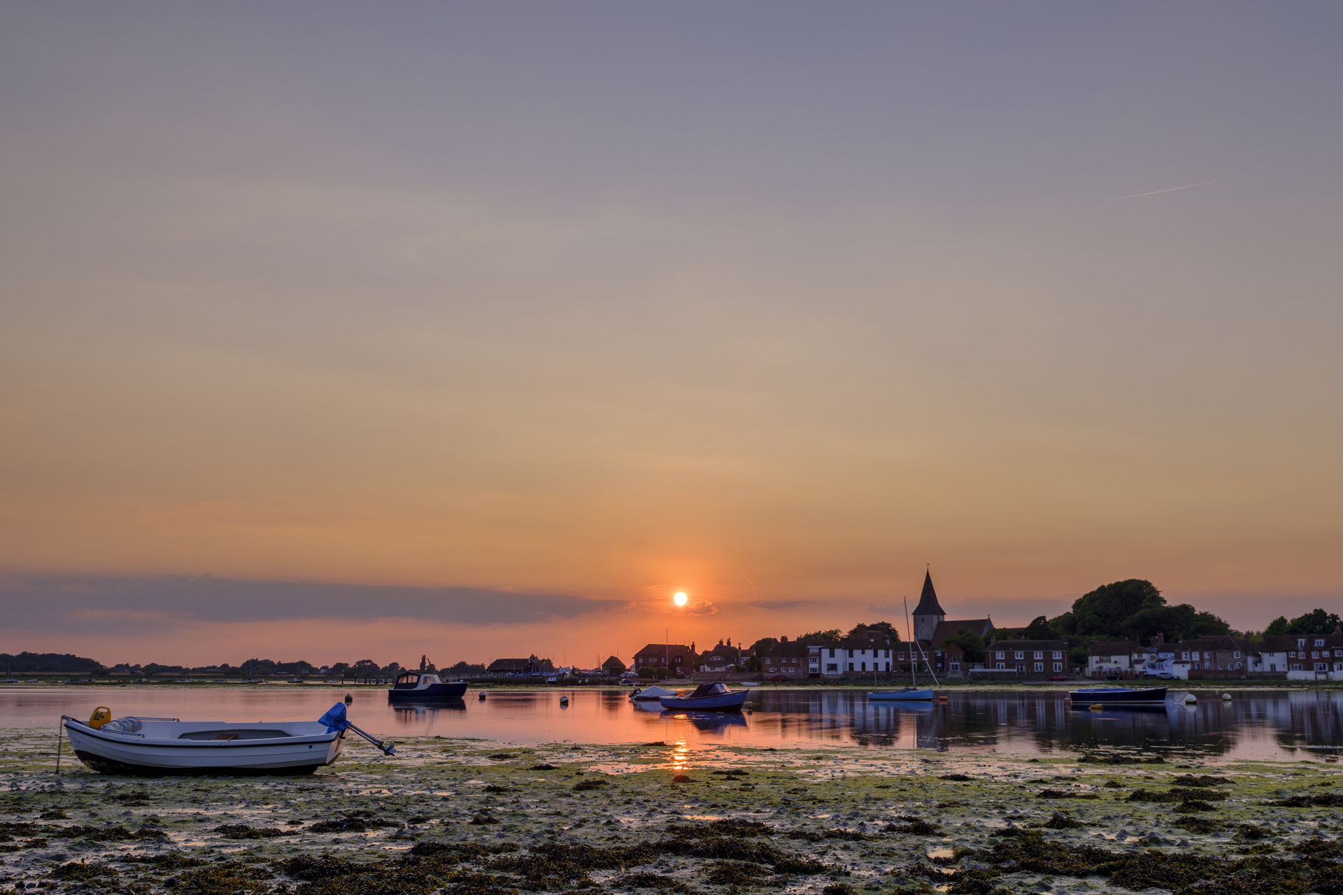 Summer sunset over Bosham Harbour and village with the church spire of Holy Trinity Church, West Sussex, UK