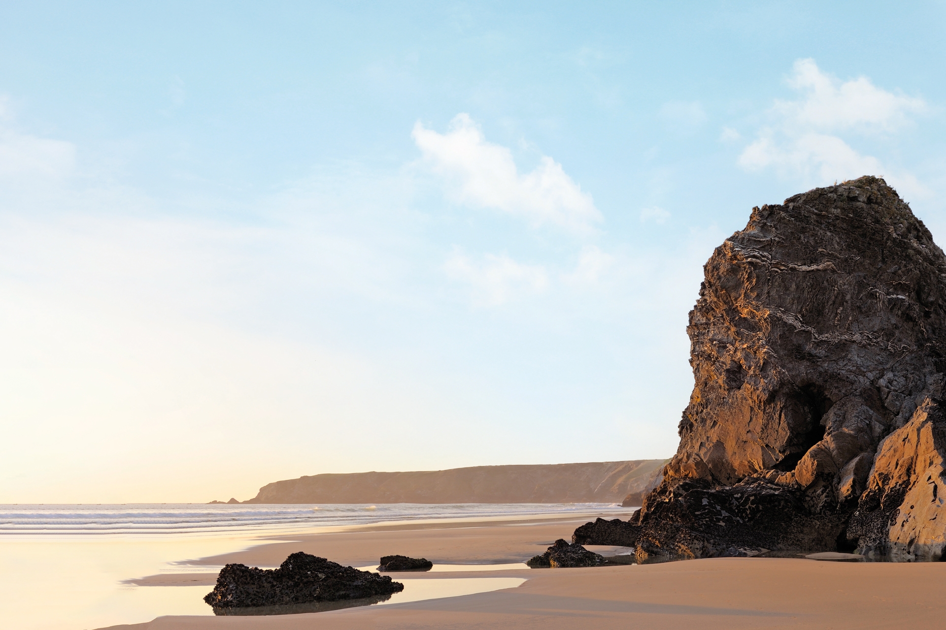 An open expanse of beach with a large rock